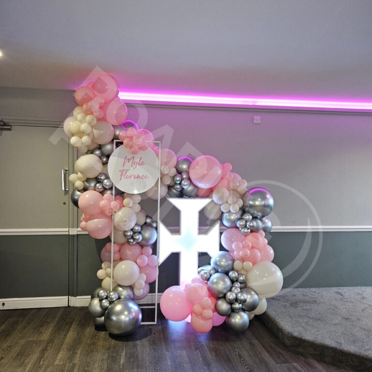 A 4ft Light Up Cross with 6ft Frame and balloon garland in pink, silver and white going around both to create a custom deluxe garland finished off with a personalised disc at Bootle FC, Merseyside.